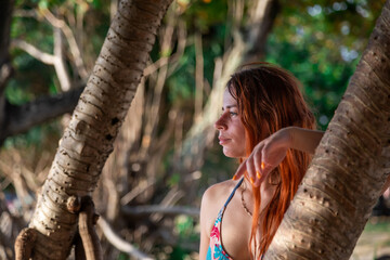 Portrait of a beautiful girl near the trees. Girl with red hair.