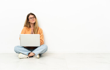Young woman with a laptop sitting on the floor scheming something