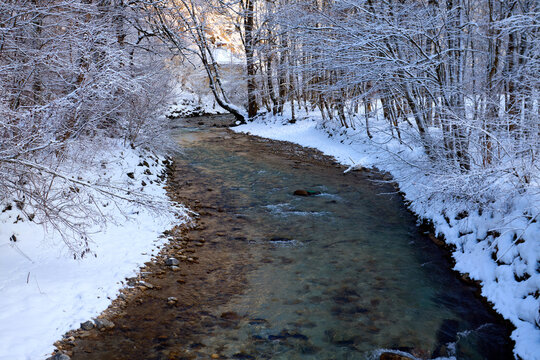 Tranquil Stream Through Snowy Village Scene
