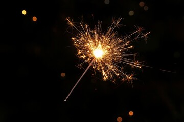 Obraz premium Sparkler burning brightly in the dark with colorful fireworks in the background