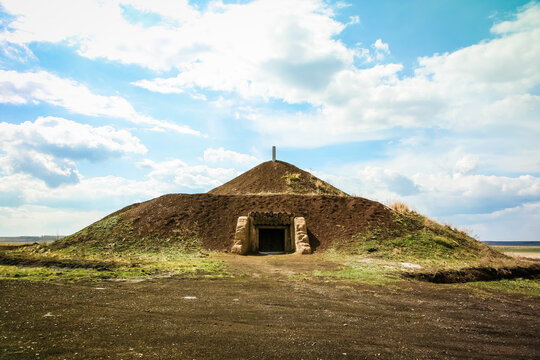 Arkaim in the southern Urals in Russia. A large mound of dirt is in the middle of a field