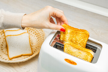 woman hand takes fried toast out of toaster, close-up. woman takes fried bread out of toaster....