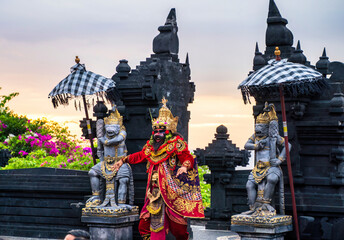 Bali, Indonesia - November 29, 2023: A vibrant depiction of Ravana during Bali’s Kecak dance, adorned in gold and red attire with a dramatic temple backdrop.