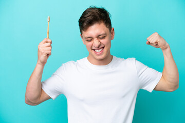 Young Brazilian man brushing teeth isolated on blue background doing strong gesture