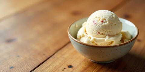Creamy vanilla ice cream with red berry bits, served in a speckled bowl on a rustic wooden table