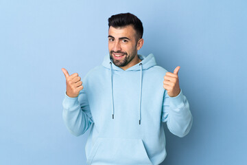 Fototapeta premium Caucasian man over isolated blue background with thumbs up gesture and smiling