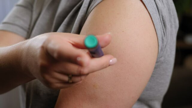 Close-up of a young woman injecting insulin into her arm with an insulin pen. Treatment of diabetes. 