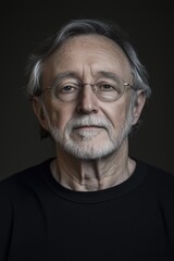 Obraz premium Thoughtful senior man with a gentle expression and distinguished features in moody lighting.