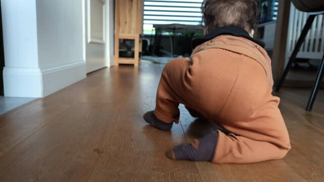 Little baby boy playfully crawling towards his mother in the living room.