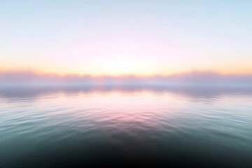 Fototapeta premium Soft pastel sunrise over a misty calm lake with gentle reflections and serene sky