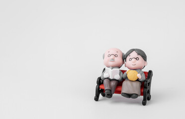 Elderly couple doll Wife sits in a chair on a white background. Concepts of financial planning and retirement. With copy space