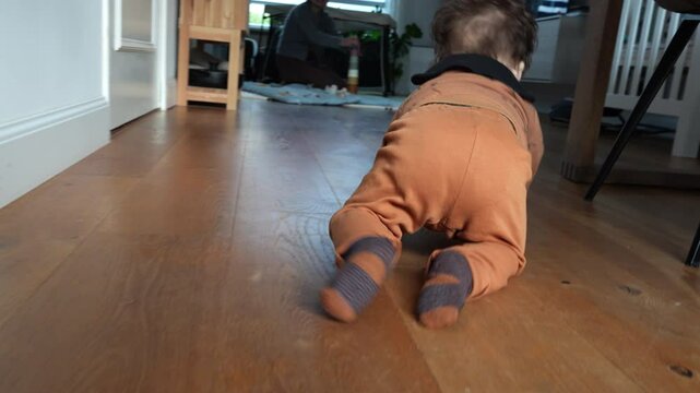 Little baby boy playfully crawling towards his mother in the living room.
