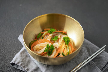 Glass noodles with vegetables and chicken in a bowl on the table. Asian cuisine