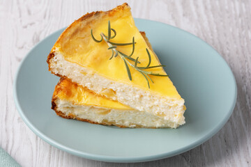 Delicious cottage cheese casserole served on a light blue plate with a sprig of rosemary accent
