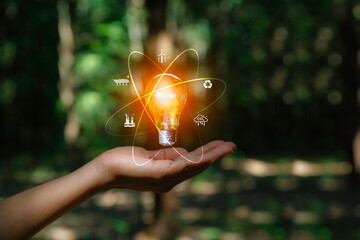 green energy, eco earth day concept. light bulb at hand on nature green background.  with...