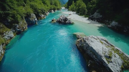 Fototapeta premium A serene turquoise river flowing between mountainous terrain, surrounded by rocks and a lush green landscape.
