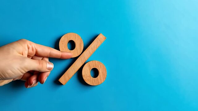 Wood percentage sign in a human hand. Blue studio background, copy space. Symbol percent. Seasonal sale, discount. Rate for finance, return. Investment ROI, credit, mortgage, tax, marketing, promotion