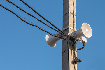 A Loudspeaker On A Pole With Wires On A Sunny Day