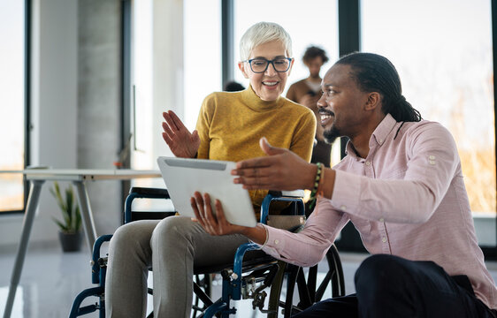 The image includes a person using a wheelchair, depicting inclusivity and teamwork in modern office - Powered by Adobe