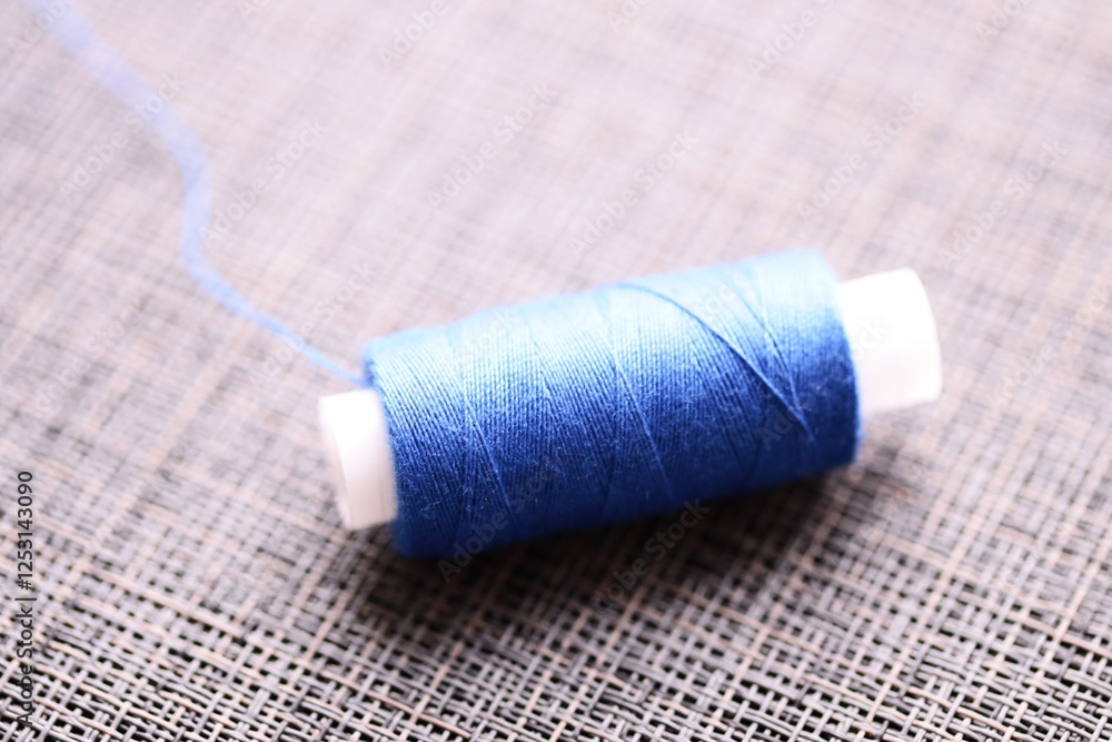 Poster a spool of thread sits on top of a table, perfect for sewing or crafting projects.