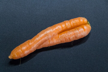 Crooked carrots on black background from organic farmer as symbol for couple in love and...