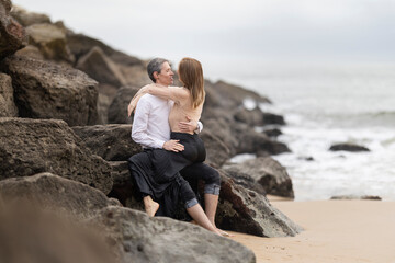 Romantic couple embracing on rocks by the ocean