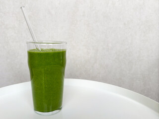 freshly blended green smoothie with spinach on gray light background. healthy and vibrant beverage....