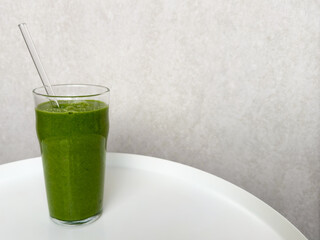 freshly blended green smoothie with spinach on gray light background. healthy and vibrant beverage....