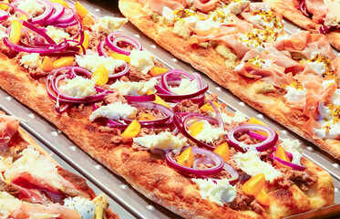many focaccia with tomato cheese mozzarella onion in showcase of pizzeria
