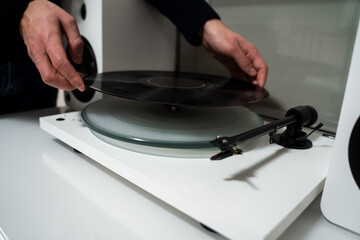 Musician hands are placing vinyl record on a turntable player. Music lover is under preparation vinyl player for playback.