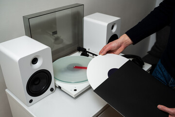 Musician changes vinyl record into turntable player and speaker system. LP tracks with modern...