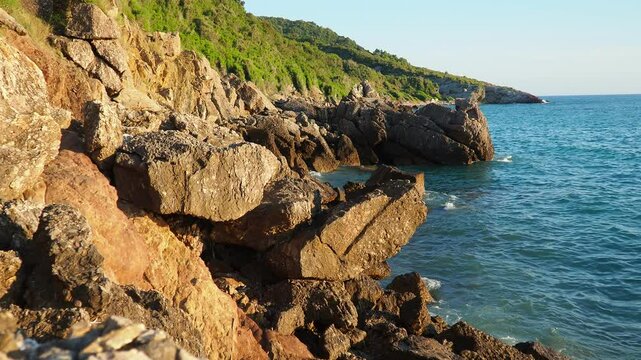 Waves gently crash against the rugged rocks while the sun sets over the horizon. Experience the serene beauty of this coastal location filled with natural wonders. Canj, Montenegro, Adriatic sea