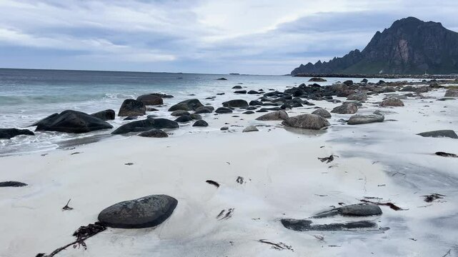 White sand beach with turquoise ocean water and a mountain in Bleik beach, Lofoten islands, Norway