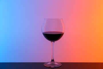 Glass of wine on table against color background