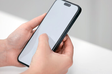 Woman dialing number on smartphone at white table against blurred background, closeup