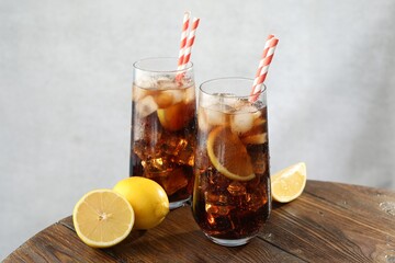 Refreshing iced cola with lemon slices on wooden table