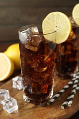 Fresh iced cola with lemon slices on wooden table, closeup