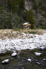 雪の残る川原と廃屋