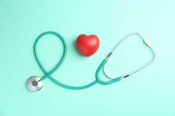 Cardiology. Stethoscope and red decorative heart on turquoise background, flat lay