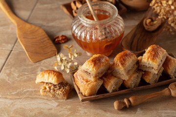 Baklava with walnuts and honey on a beige background.