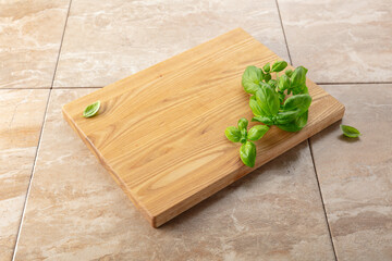 Cutting board and basil on a kitchen table.