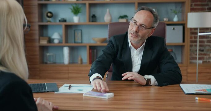 Mature businessman refusing from money bribe given by woman at office. Corruption concept.