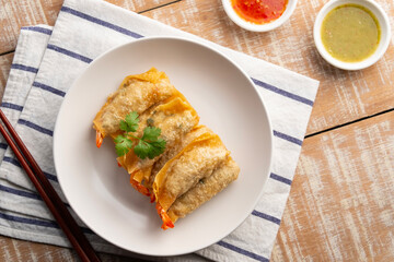 Deep Fried Crispy Wonton wrapped with shrimp and minced pork in white plate.Thai appetizer food with Sweet Chili Sauce and seafood sauce.Top view.