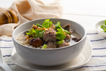 Pork Porridge.Boiled rice with Pork Baby Back Ribs or pork cartilage with shitake mushroom in white bowl.Asian breakfast style