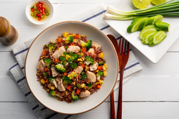 Healthy asian food.Thai fried Organic Red Brown Jasmine Rice (unpolished rice) with chicken breast and broccoli carrot egg in white plate.clean food.Top view.