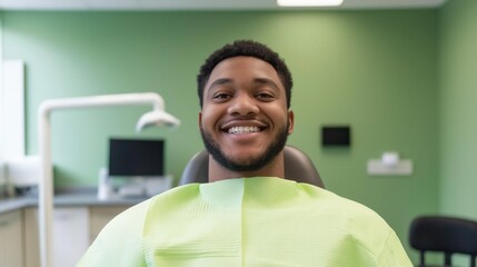 Confident Black man smiles broadly while seated in a dental chair in a clinic, celebrating National Dentists Day