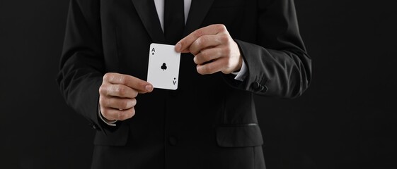 Illusionist showing playing card on black background, closeup