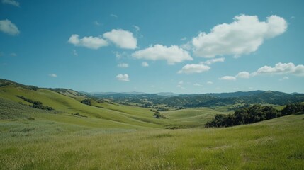 Rolling green hills under a blue sky dotted with fluffy white clouds creating a beautiful serene landscape