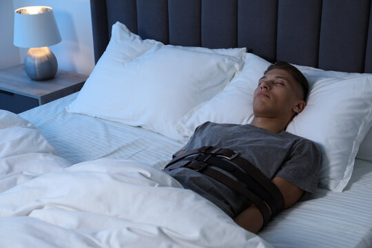 Sleepwalker fastened with belts lying in bed
