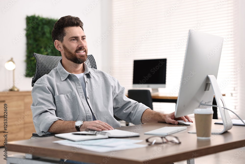 Poster man working on computer at table in office